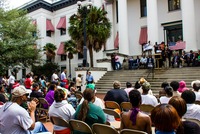 Spectators watch a woman giving a speech during the post-march rally for Trayvon Martin on the western steps of the Old Capitol (1845) on the forty-fourth anniversary of Dr. Martin Luther King, Jr.'s assassination.