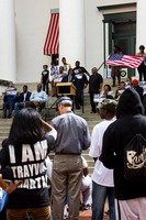 Spectators watch Representative Alan Williams giving a speech during the post-march rally for Trayvon Martin on the western steps of the Old Capitol (1845) on the forty-fourth anniversary of Dr. Martin Luther King, Jr.'s assassination.