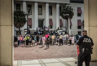 An FDLE police officer stands by as spectators watch a man giving a speech during the post-march rally for Trayvon Martin on the western steps of the Old Capitol (1845) on the forty-fourth anniversary of Dr. Martin Luther King, Jr.'s assassination.