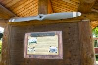 A propeller and informational poster from the Talkeetna Historical Society in a small wooden pavilion at the northern end of the Talkeetna Village Airstrip [AK44] (1940).