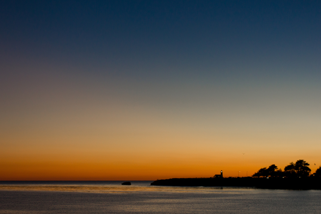 Day fades to night at Point Santa Cruz and the Mark Abbott Memorial Lighthouse (1967) at Steamer Lane from the southern tip of the Santa Cruz Wharf (1914).