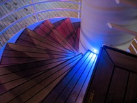 Blue lighting on a spiral staircase to the Deck 10 pool area, seen from the Deck 11 port exterior corridor on Carnival Sensation.