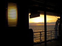 The sun sets over the Atlantic Ocean from inside a Deck 10 starboard interior corridor near lifeboat embarkation station 17 on Carnival Sensation.