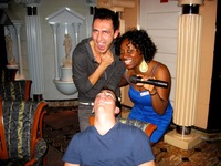 An amused passenger and karaoke host Aretha pose by a drunken passenger who wandered in, sat down and passed out during the LGBT meet at Michelangelo Lounge, Deck 9 on Carnival Sensation.