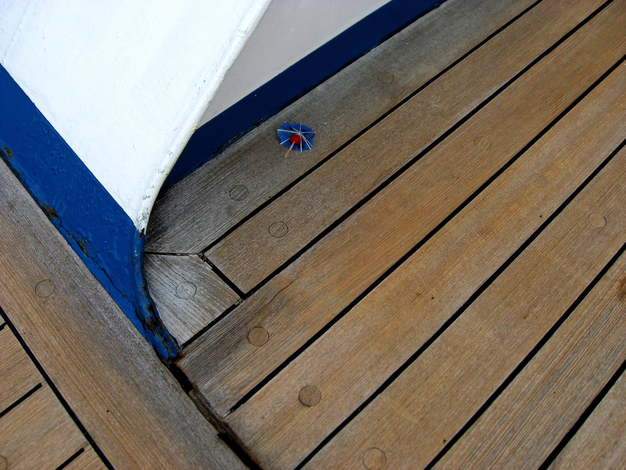 Paradise Lost: discarded cocktail cherry and umbrella on the deck in the entryway to the Deck 11 forward lookout above the bridge on Carnival Sensation.