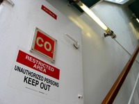 'Electrical,' 'CO2' and 'Restricted Area Unauthorized Persons Keep Out' signs on a door in a stairwell to Deck 12, seen from the Deck 11 forward lookout above the bridge on Carnival Sensation.
