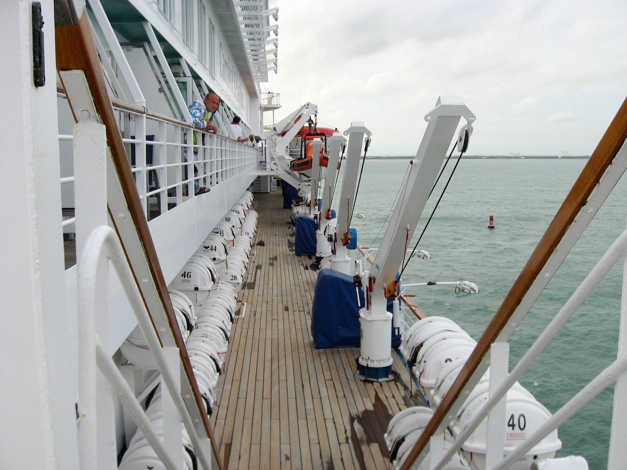 Looking back at the Deck 10 port forward exterior corridor while sailing into the Atlantic Ocean guided by the Port Canaveral channel markers, seen from the Deck 11 forward lookout above the bridge on Carnival Sensation.
