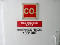 'CO2' and 'Restricted Area Unauthorized Persons Keep Out' signs on a door in a stairwell to Deck 12, seen from the Deck 11 forward lookout above the bridge on Carnival Sensation.