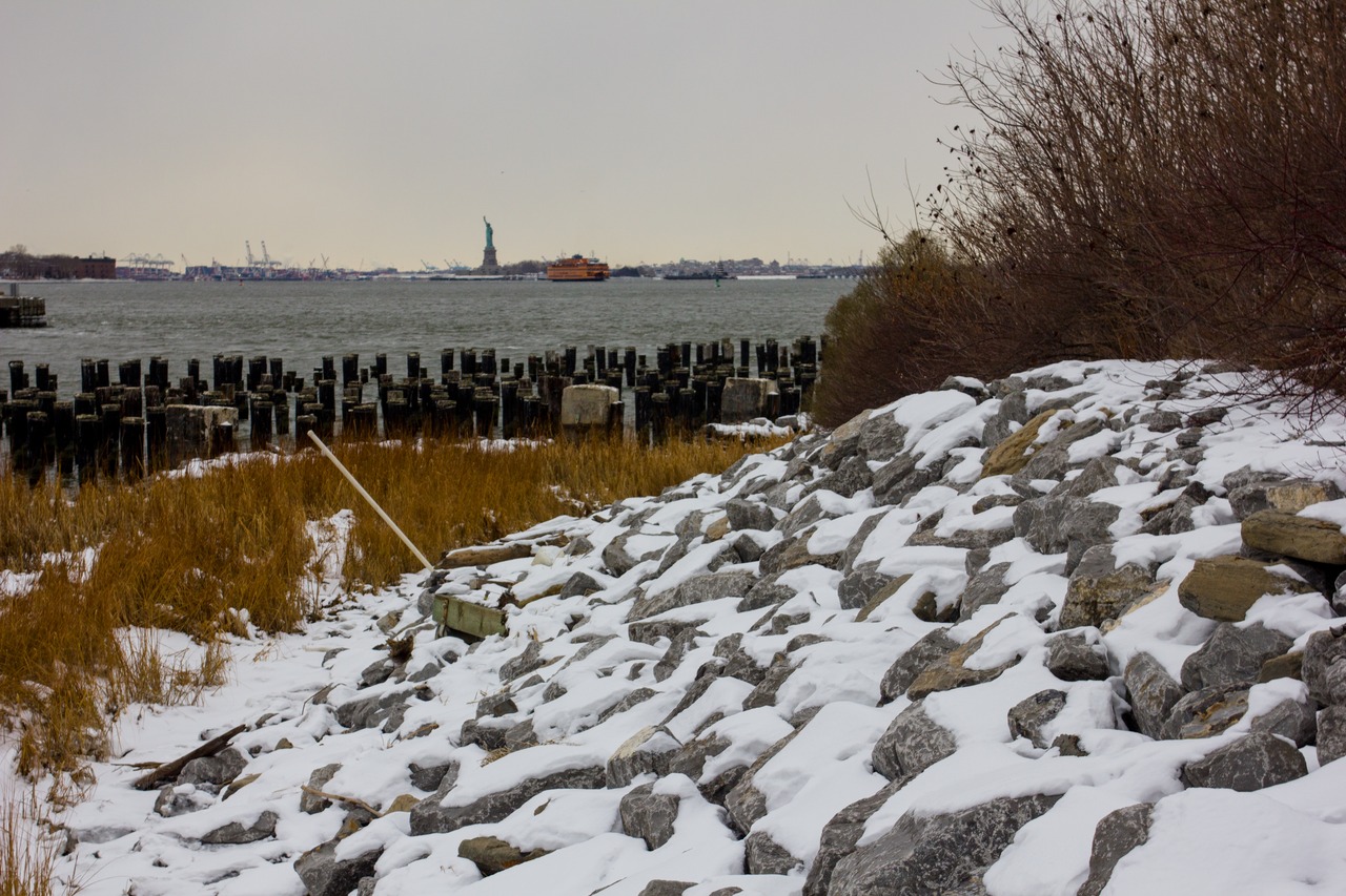 The Statue of Liberty (1886), Staten Island Ferry, centenarian wood pylons in the East River, smooth cordgrass (Spartina alterniflora) and granite salvaged from the old Willis Avenue Bridge (1901–2011) at Brooklyn Bridge Park (2010) Pier 1.
