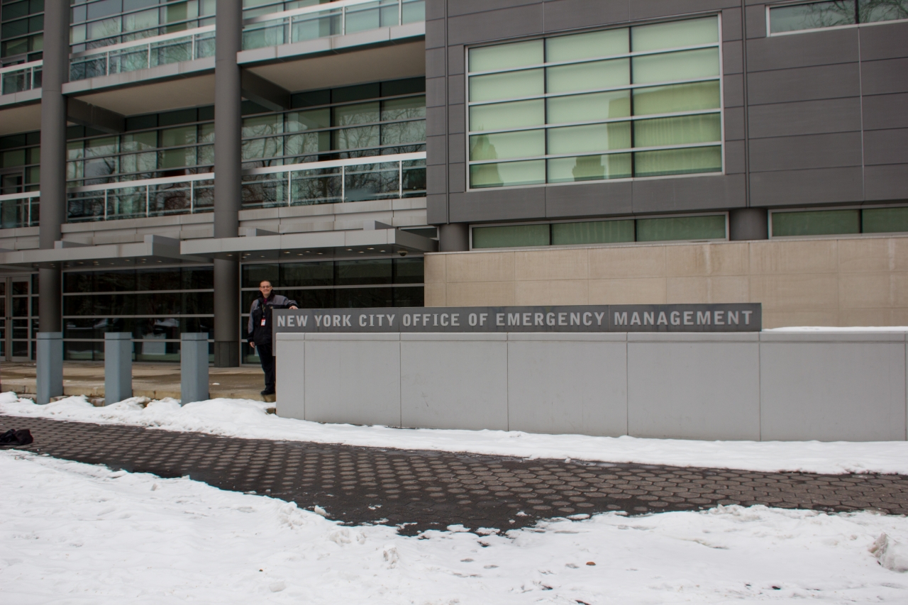 David July and the NYC OEM sign in front of the New York City Office of Emergency Management building (1955) after concluding a tour of the Watch Command and Emergency Operations Center.