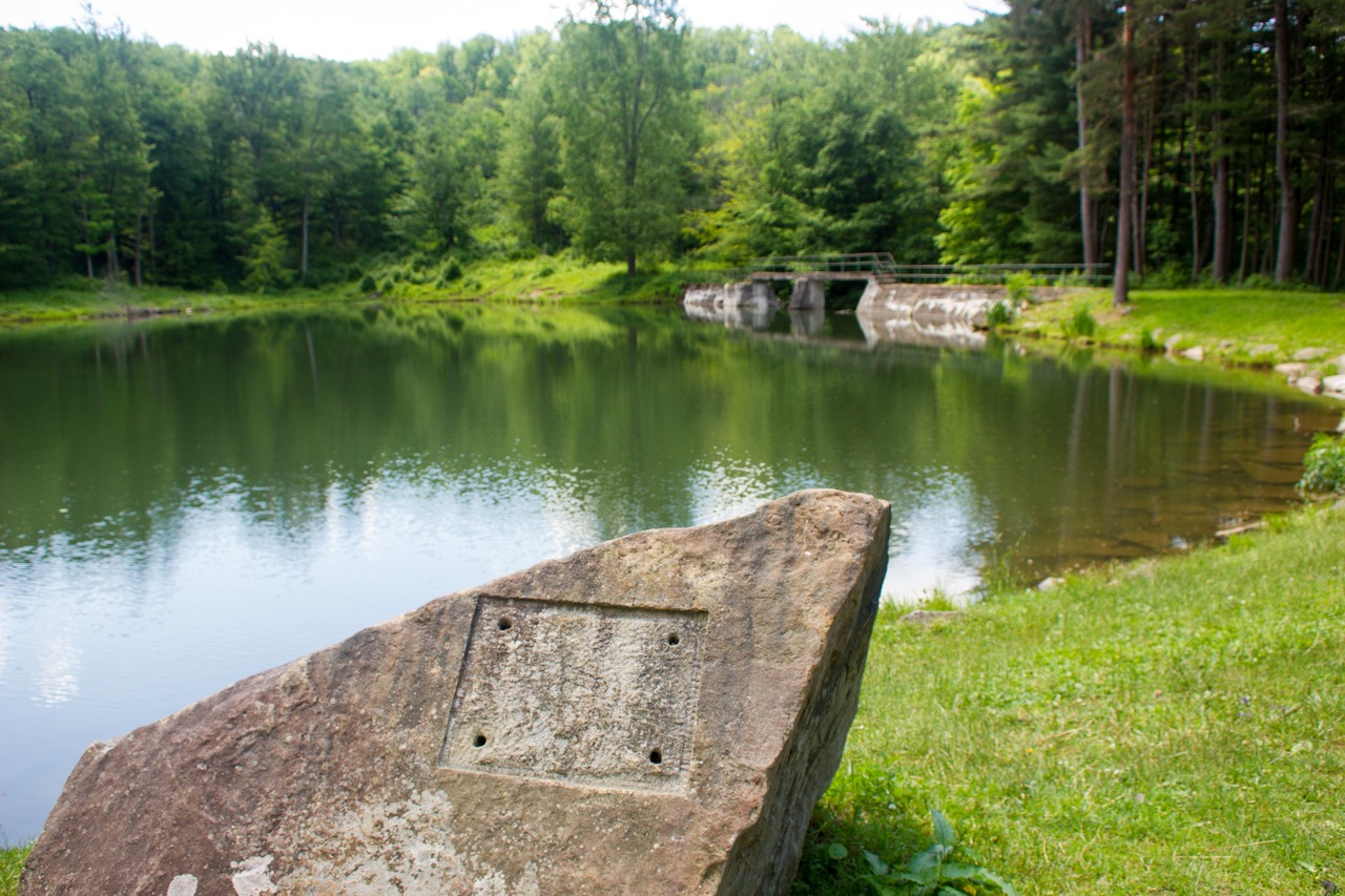 A rock with a missing sign along the shore of Science Lake near the Science Lake Dam (1926) in Allegany State Park.