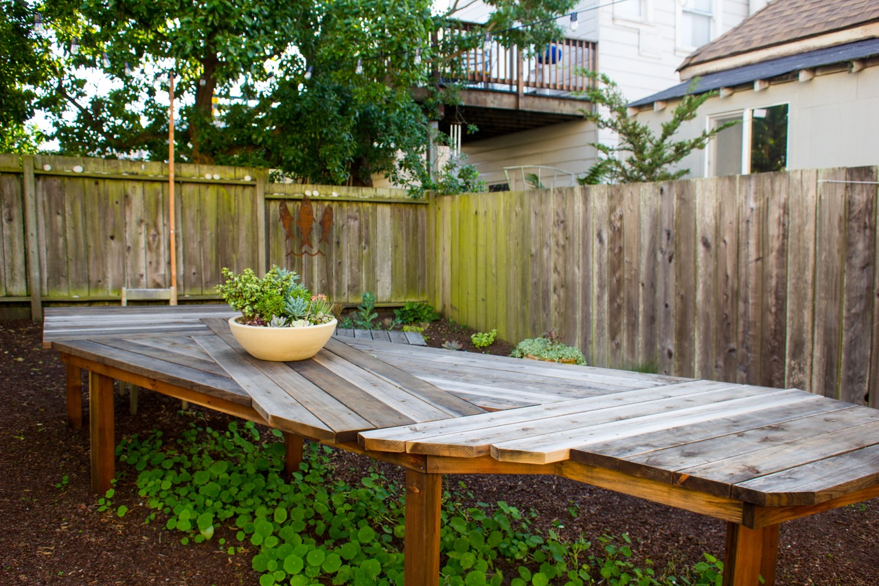Eric Rewitzer's wooden California table and the studio's logo in metal in the spacious backyard of 3 Fish Studios.