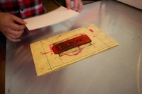 Eric Rewitzer places paper over the painted linoleum sheet carved with Sutro Tower artwork in preparation for a hand pulled linocut print.