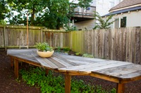 Eric Rewitzer's wooden California table and the studio's logo in metal in the spacious backyard of 3 Fish Studios.