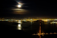 The moon rises over San Francisco Bay and Alcatraz Island with the Golden Gate and Oakland Bay Bridges in view from near Hawk Hill in the Marin Headlands.