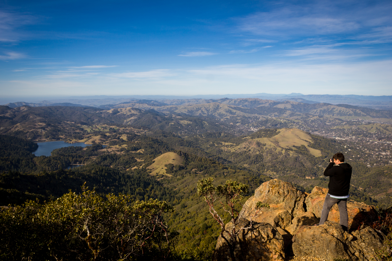 Marc Malonzo photographs the landscape of redwood and oak forests and Bon Tempe Lake reservoir from atop the Mount Tamalpais East Peak summit at the end of the Plank Walk Trail in Mount Tamalpais State Park.