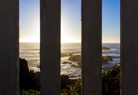 Pacific Ocean sunset through the posts of the wooden platform on the edge of the rocky promontory upon which the Pigeon Point Lighthouse (1871) is built.
