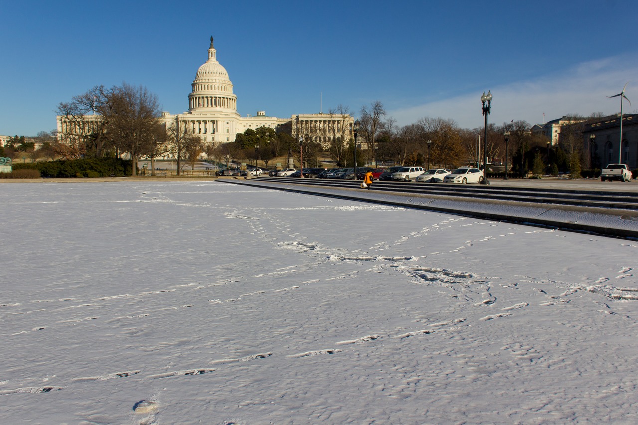 Footprints in the snow show where people walked over the completely frozen Capitol Reflecting Pool (1971) near the United States Capitol (1811/1866) and United States Botanic Garden (1867).