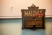 Antique metal match holder complete with wooden matches hung from a nail on the kitchen wall in the Woodrow Wilson House (1915).