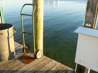 Trash can and hand truck on the HarborWalk Marina dock next to The Lucky Snapper Grill & Bar.