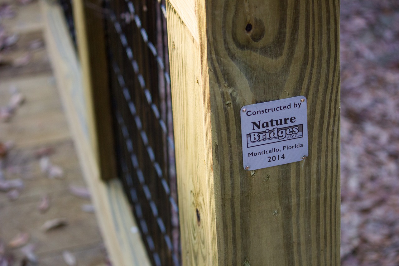 Tag for Nature Bridges of Monticello on the boardwalk portion of the new pedestrian bridge (S/N 13B028) over the CSX railroad line in Lafayette Heritage Trail Park near J.R. Alford Greenway.