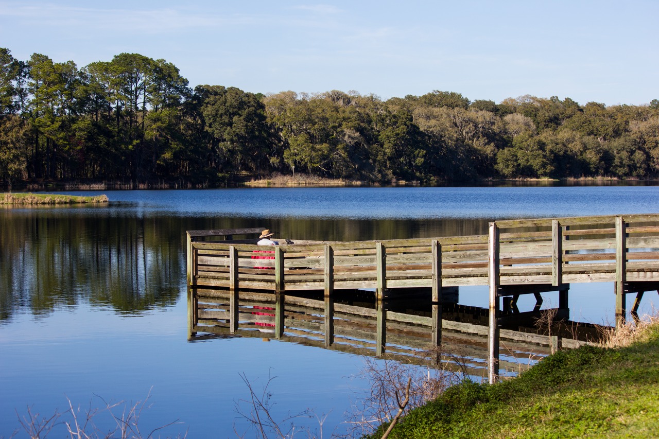 A man fishing on a small wooden pier on Piney Z Lake off Fishing Finger 2 in Lafayette Heritage Trail Park.