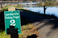 A man fishing in Piney Z Lake beyond the sign for Fishing Finger 2 in Lafayette Heritage Trail Park.