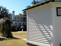 White clapboard building on Carriage Circle in front of the The east wing (1914) of the main house at Pebble Hill Plantation.
