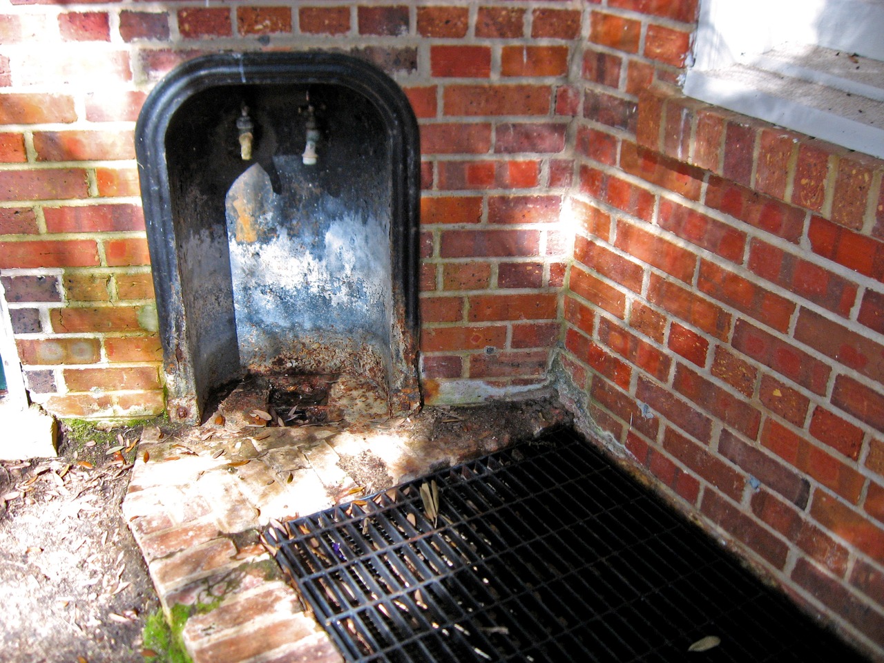 Two water faucets and a metal grate in the Stable Complex (1928) courtyard at Pebble Hill Plantation.