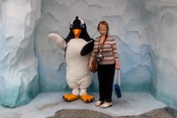 Mom posing with a penguin character at 'Antarctica: Empire of the Penguin' at SeaWorld Orlando.