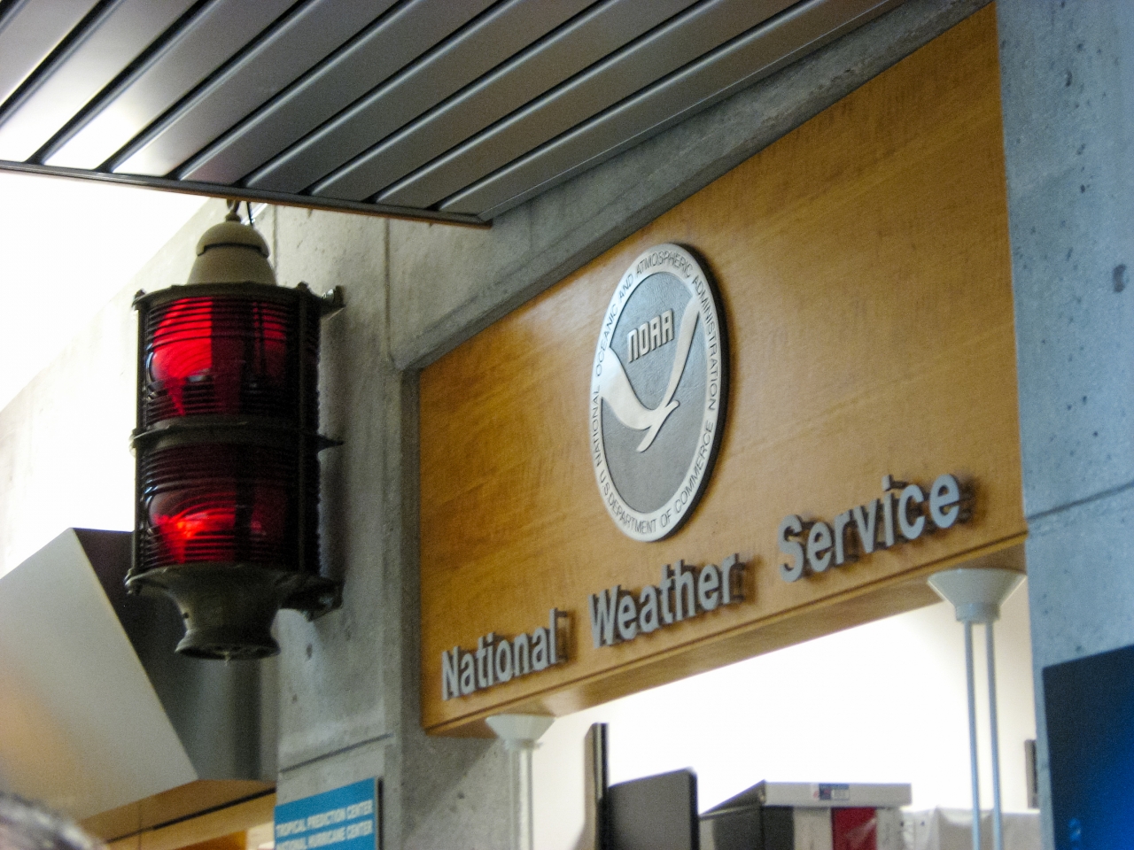 NOAA logo, NWS sign and a red navigational beacon above the lobby security desk at the National Hurricane Center.