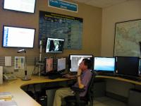 A NOAA staffer operates a console at the Pacific/Classification Desk in the Tropical Analysis and Forecast Branch unit of the National Hurricane Center.