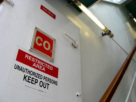 Photo Credit: David July — ‘Electrical,’ ‘CO2’ and ‘Restricted Area Unauthorized Persons Keep Out’ signs on a door in a stairwell to Deck 12, seen from the Deck 11 forward lookout above the bridge on Carnival Sensation, Atlantic Ocean, off the coast of Florida, 10 March 2011