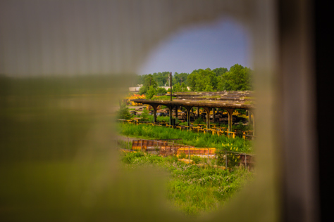 Photo Credit: David July — Eastern train platforms at Buffalo Central Terminal (1929) now owned by CSX and Amtrak seen through a broken window in the terminal's main floor ticket receivers room, Buffalo, New York: 28 June 2014