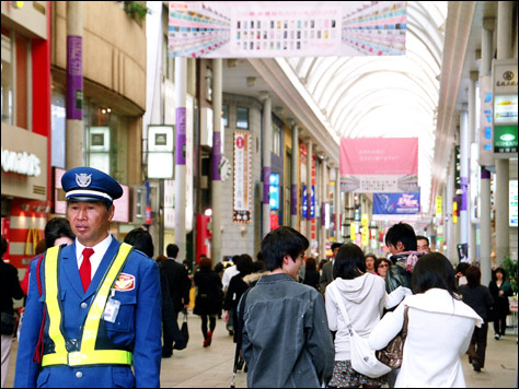 Photo Credit: Carol Nichelson — A security officer stands on duty at a vehicular intersection through the Hondori shopping arcade, Hiroshima, Japan, 18 March 2008