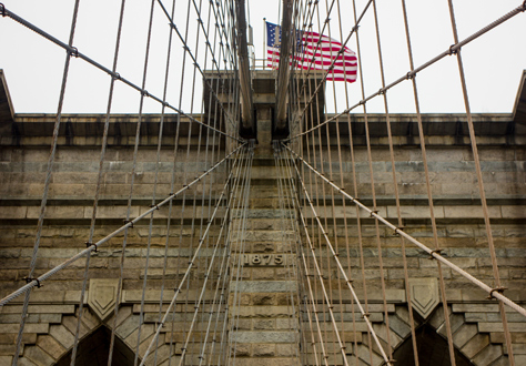 Photo Credit: David July — Two center cables leading up to the eastern side of the western tower of the Brooklyn Bridge (1883) from the pedestrian and cyclist promenade, Manhattan, New York: 26 January 2014