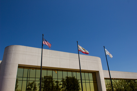 Photo Credit: David July — Front entrance and triad of flags at the front of 400 National Way (1984), the fictional PlayTronics headquarters building in 'Sneakers' (1992), Simi Valley, California: 22 August 2013