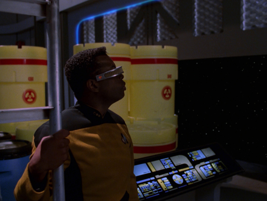 La Forge watches as the cargo bay door opens with stacks of overpack drums behind