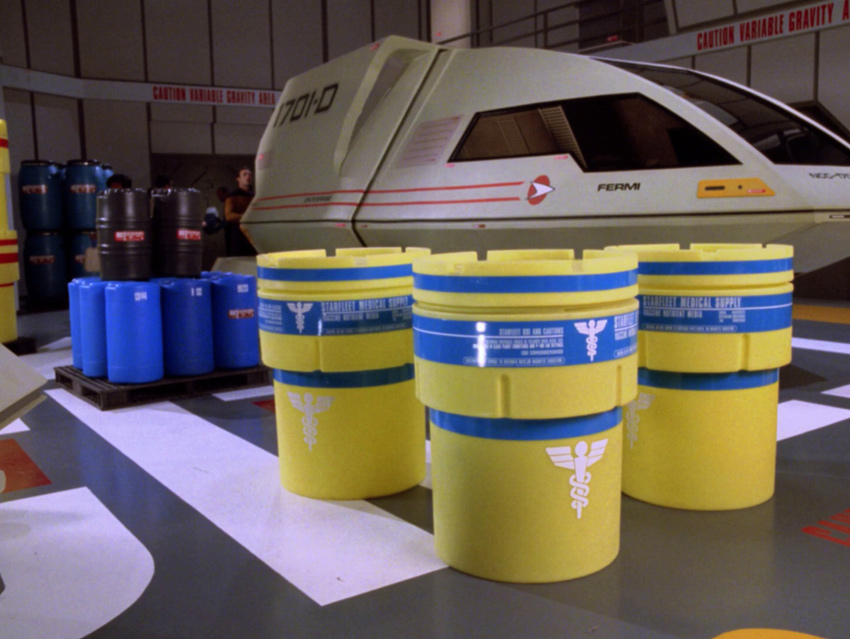 Medical-use overpack drums on the shuttlebay floor in front of shuttlecraft Fermi