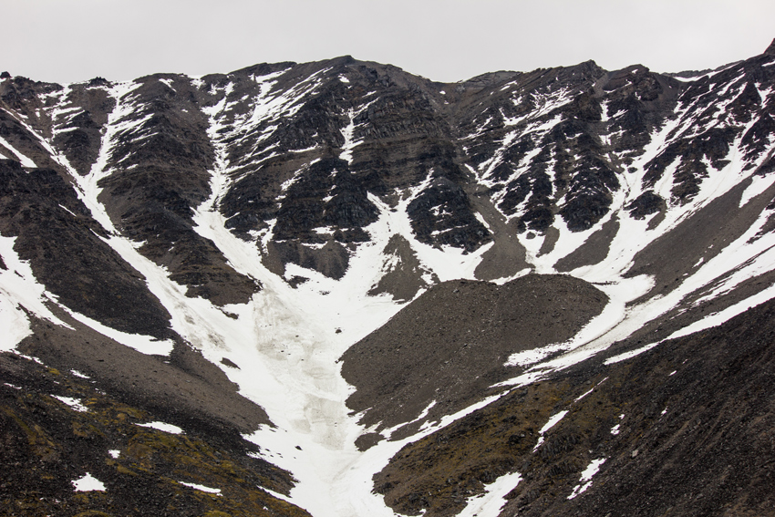A partially snow-covered mountain of the Brooks Range at Atigun Pass (elevation 4,739 feet) at the Slide Path 23 pullout where the James W. Dalton Highway crosses the Continental Divide.