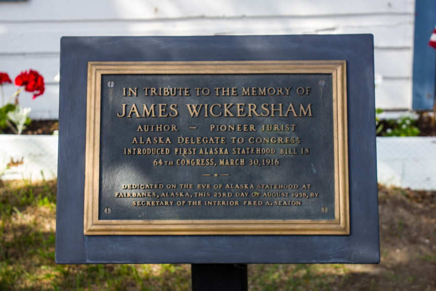 A memorial tribute plaque mounted to a pole outside of the Wickersham House (1904) museum in Pioneer Park.