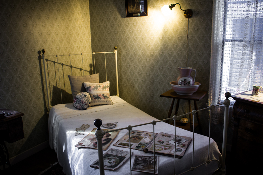 A bed with antique periodicals and personal affects on it in a bedroom of the Wickersham House (1904) museum in Pioneer Park.