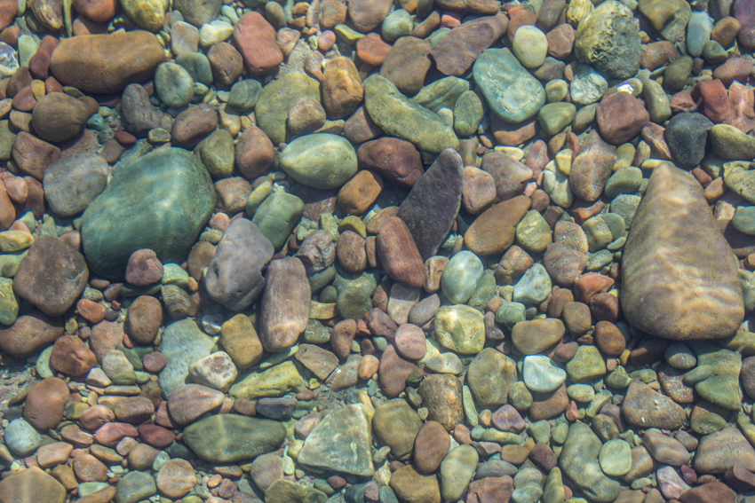 Multicolored rocks lining the bottom of Lake McDonald, extremely clear and lacking plankton due to its cold temperature, from the Apgar Village boat ramp dock in Glacier National Park.